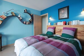 A bedroom with a bed, a bookshelf, and a door.