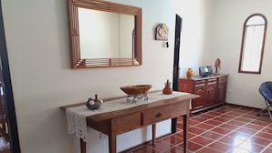 Une pièce avec une table en bois, un miroir, un sol carrelé et un meuble.