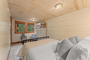 A bedroom with a bed, dresser, window, and ceiling light.