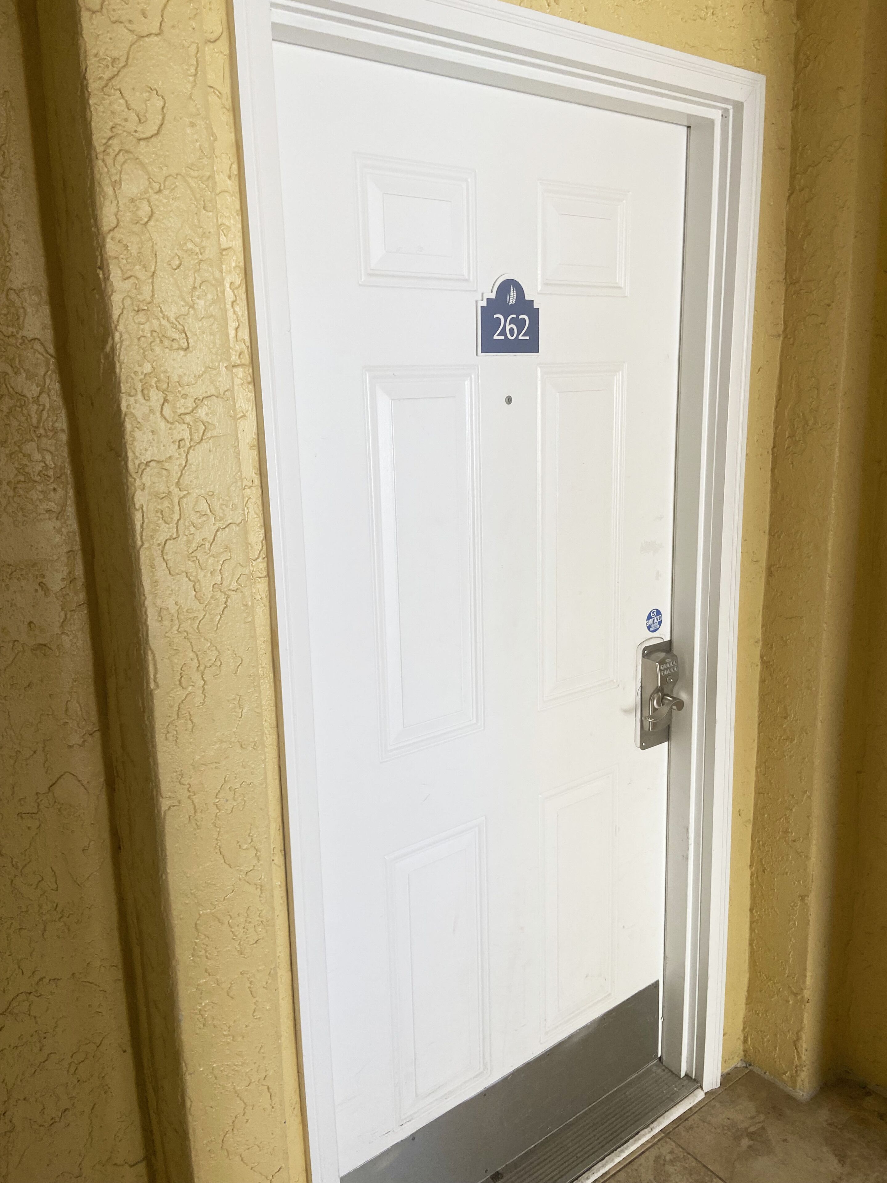 A white door with a number plate "262" and a blue sign above it.