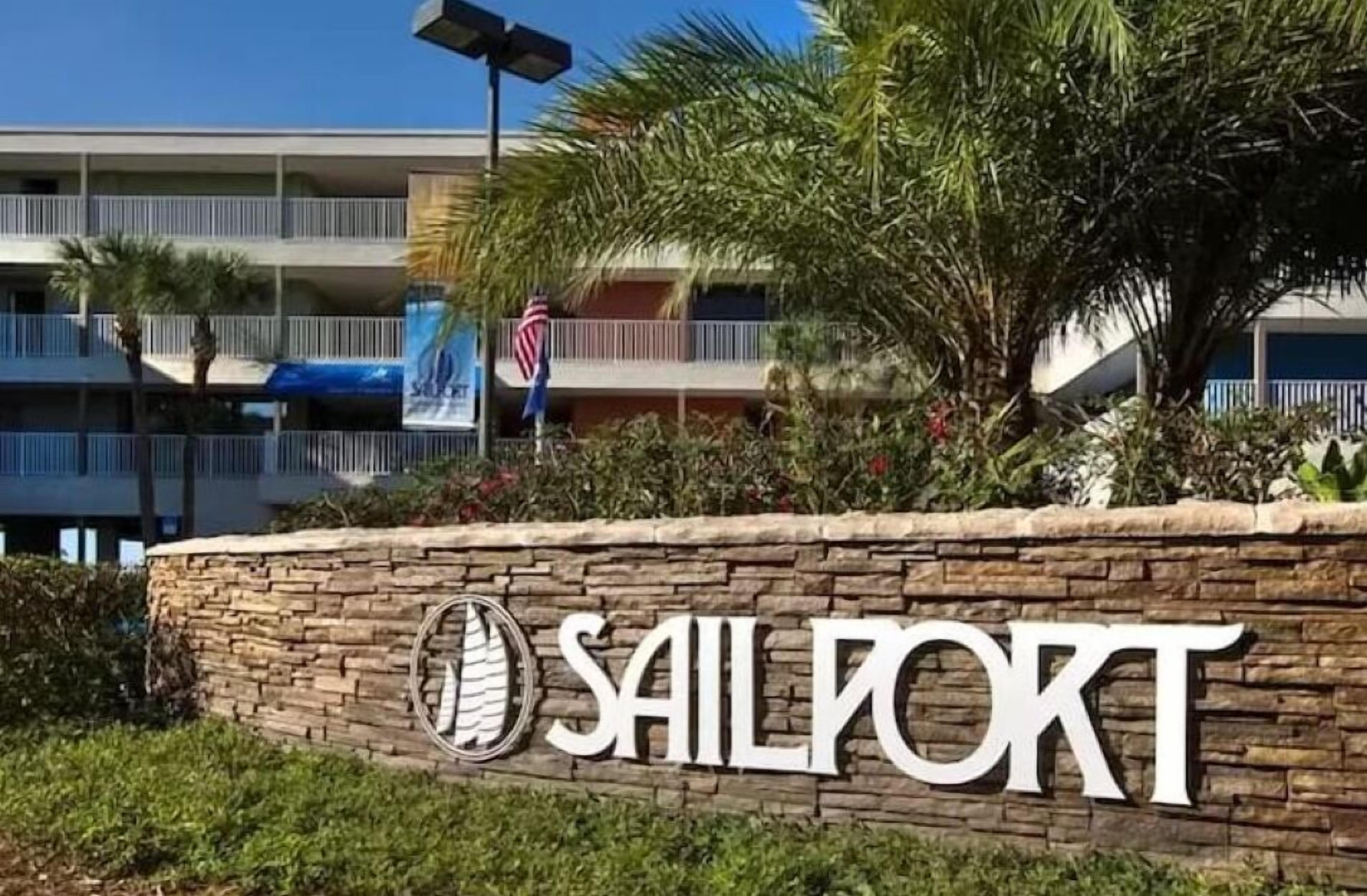 Un muro di pietra con il testo "SAILPORT" e il logo di una barca a vela.