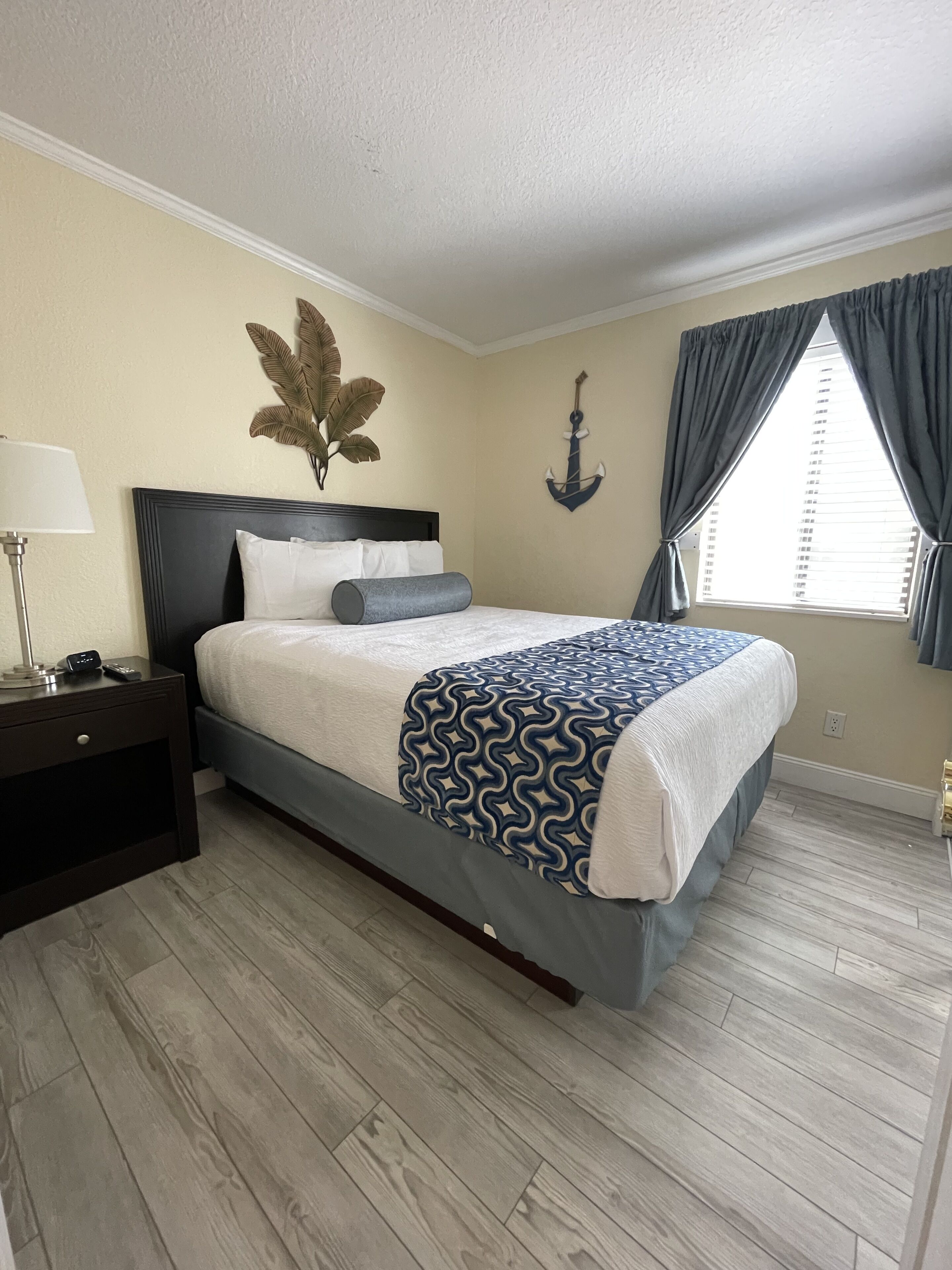 A bedroom with a bed, nightstand, lamp, and decorative wall art.