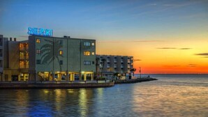 Ein Hotel mit einem Schild mit der Aufschrift "SAILPORT" im Abendlicht, mit Blick auf das Wasser und einer ruhigen See.