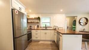 Une cuisine moderne avec des meubles blancs, des appareils en acier inoxydable et un plan de travail en bois.