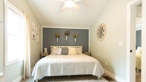 Une chambre à coucher comprenant un lit, un ventilateur de plafond, une table de chevet et des jardinières fixées au mur.
