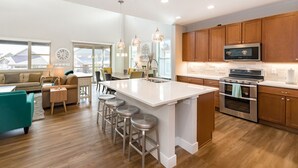 A modern kitchen with wooden cabinets, stainless steel appliances, and a large island with bar stools.