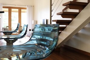 A modern interior with a staircase, a dining area with glass chairs, and a view through large windows. - Barefoot Luxury - Pool & Walk To Holetown Beach (Holetown)