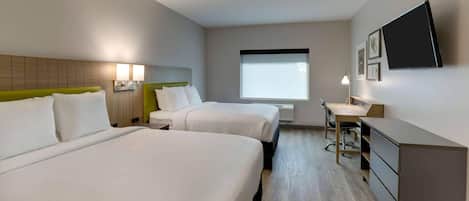 Habitación de hotel con dos camas, un escritorio, una silla, un televisor y una ventana.