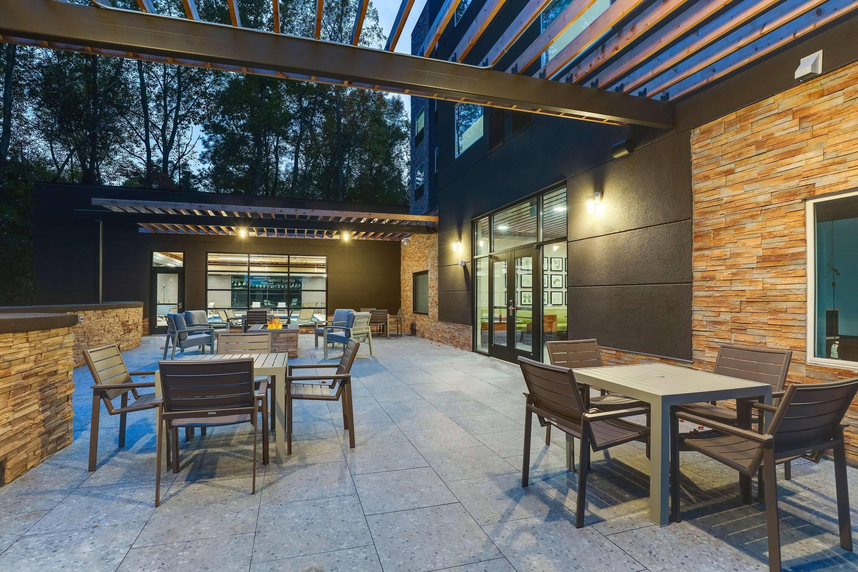 Un patio al aire libre con mesa y sillas, una pérgola y un muro de piedra.
