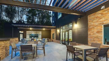 Un patio al aire libre con mesa y sillas, una pérgola y un muro de piedra.