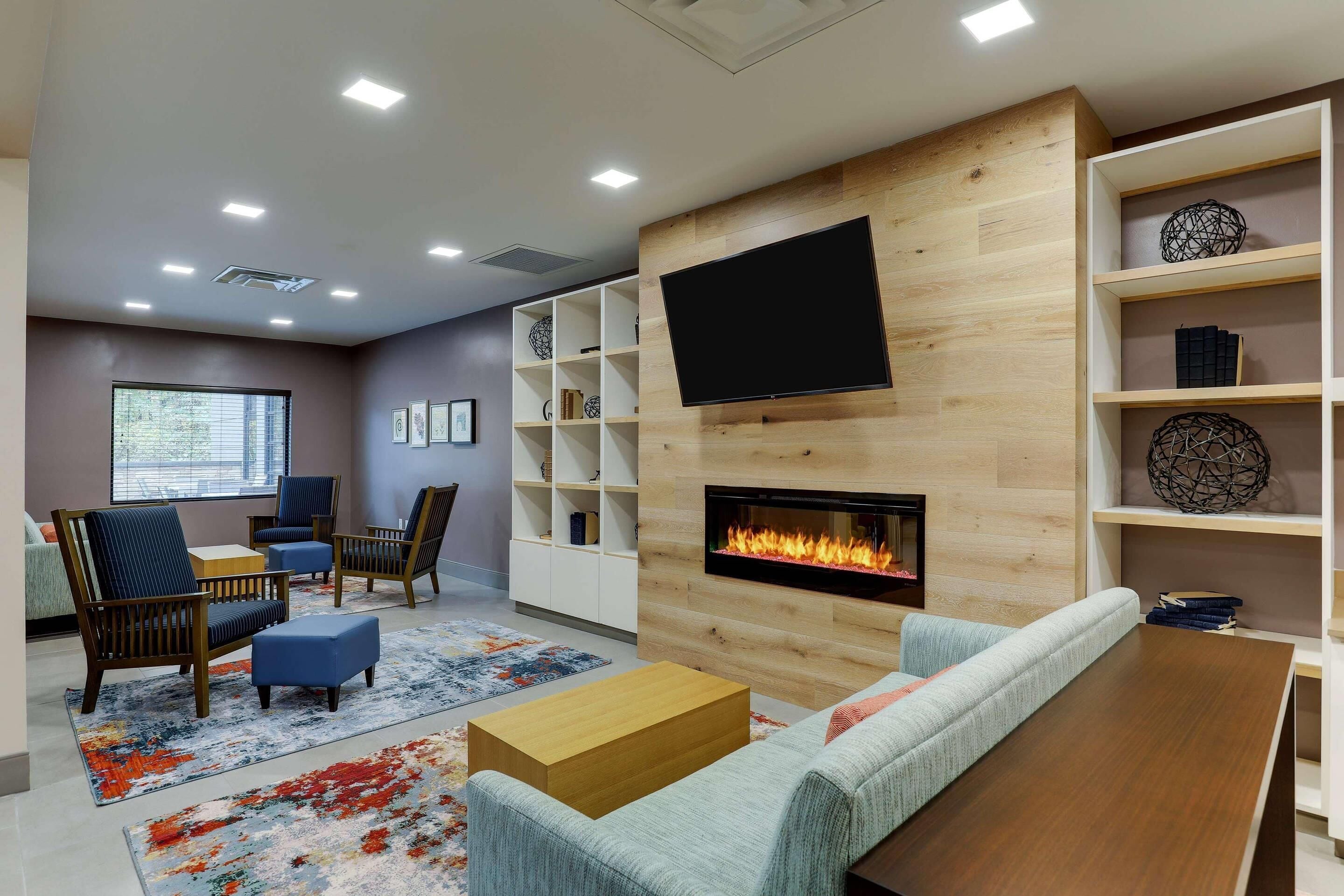 A modern living room with a fireplace, seating area, and built-in shelves.