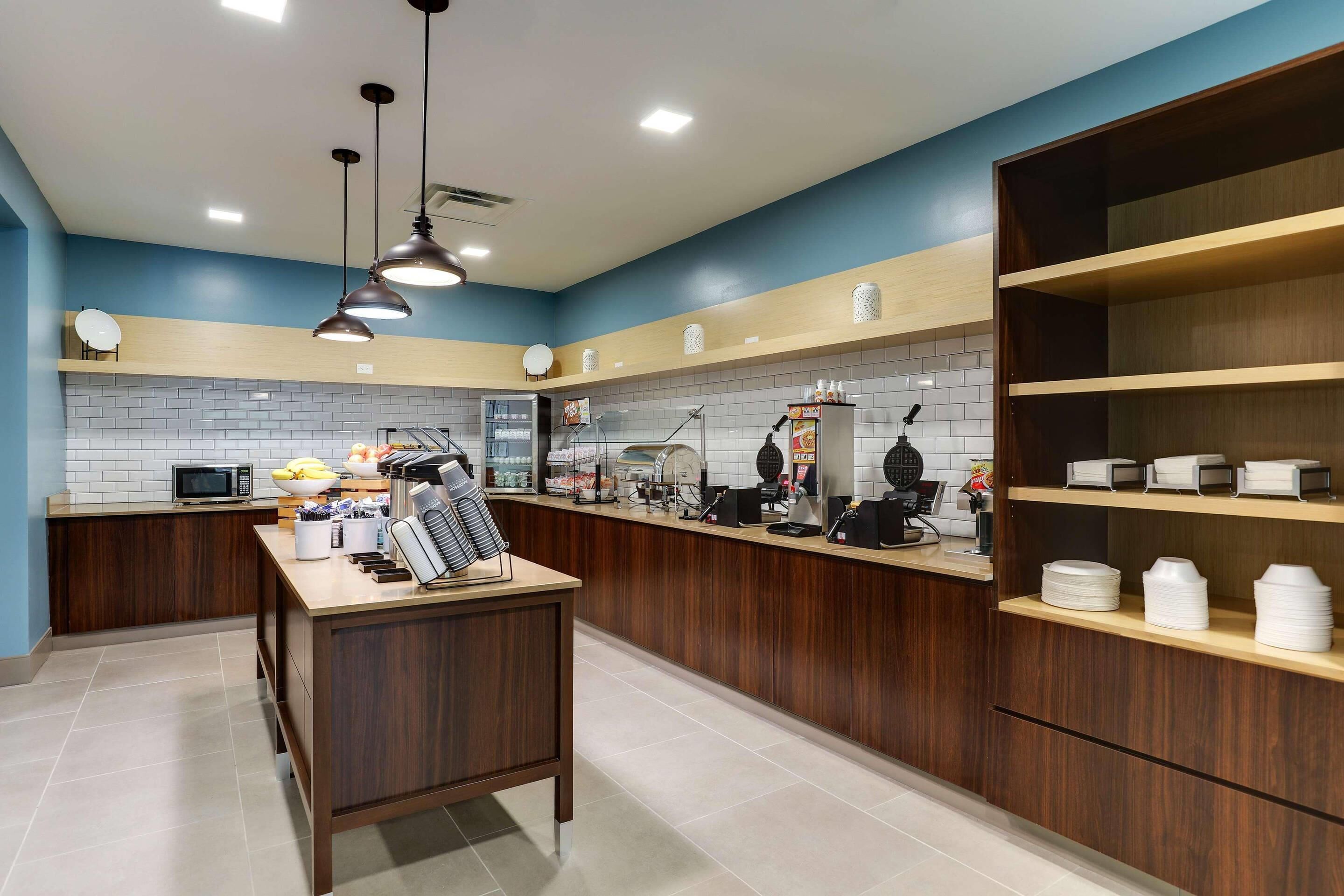 A modern kitchen with a central island, built-in appliances, and wooden shelving.