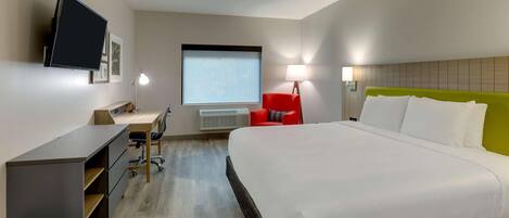 A hotel room with a bed, desk, chair, TV, and window.