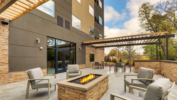 An outdoor patio with a fire pit, seating, and a pergola.