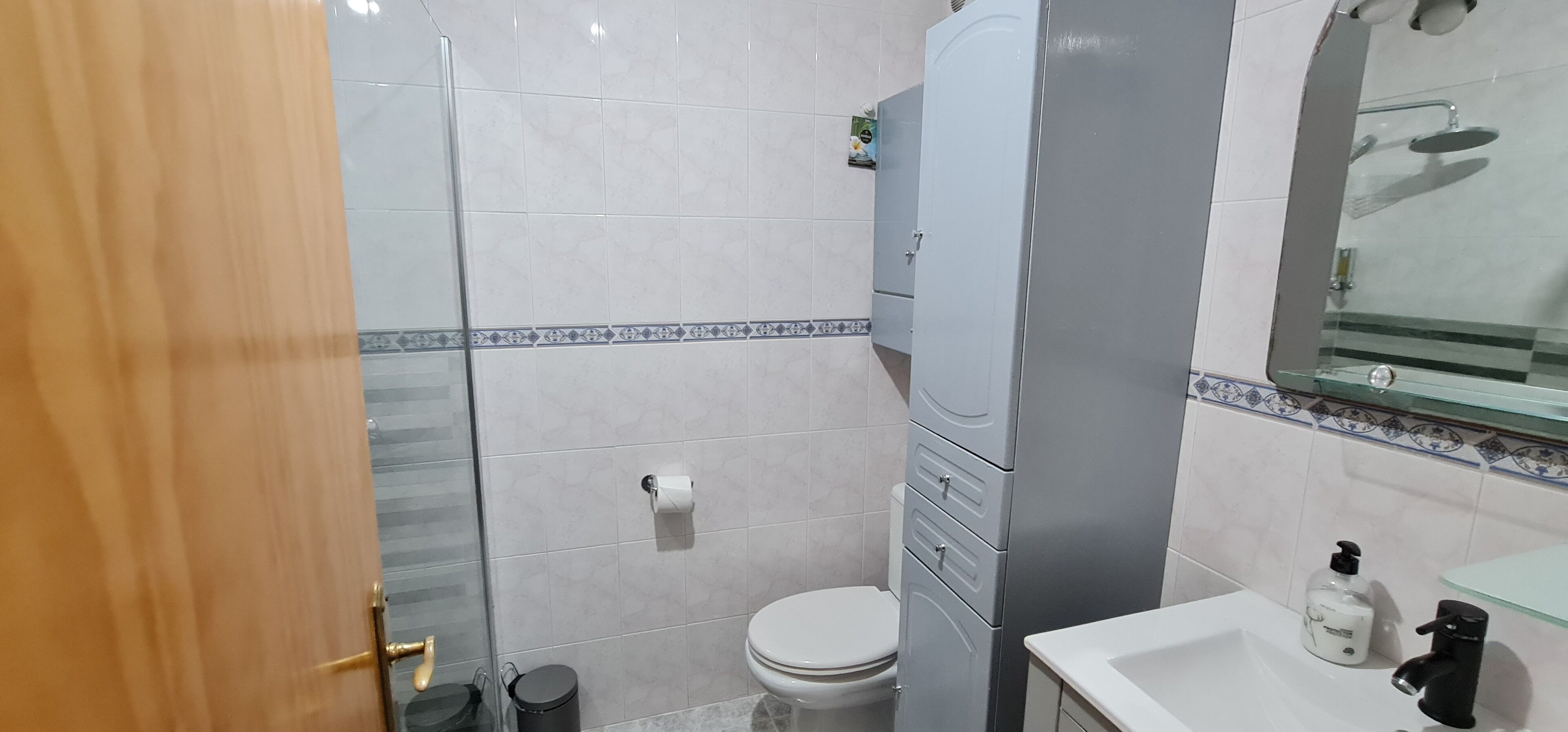 A bathroom with a toilet, a sink, a mirror, and a shower.