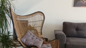 A living room with a wicker chair, a grey sofa, a small table, and a potted plant. - Surise Den- Walk to the beach, sea view and pool. Holiday rentals & winter stays (Puerto de Mazarrón)