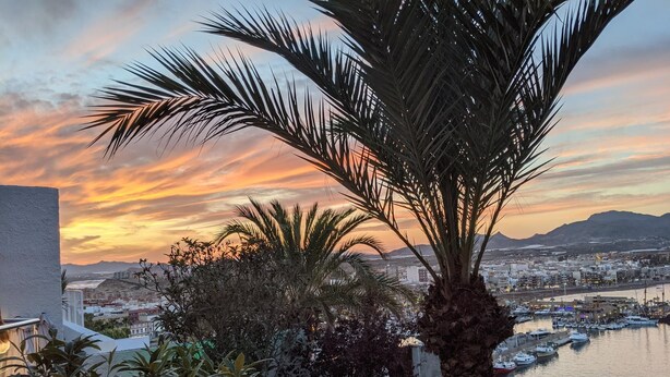 A balcony with a view of a marina and cityscape during sunset. - Surise Den- Walk to the beach, sea view and pool. Holiday rentals & winter stays (Puerto de Mazarrón)