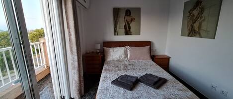 A hotel room with a bed, a nightstand, a painting on the wall, and a view of the outside balcony.