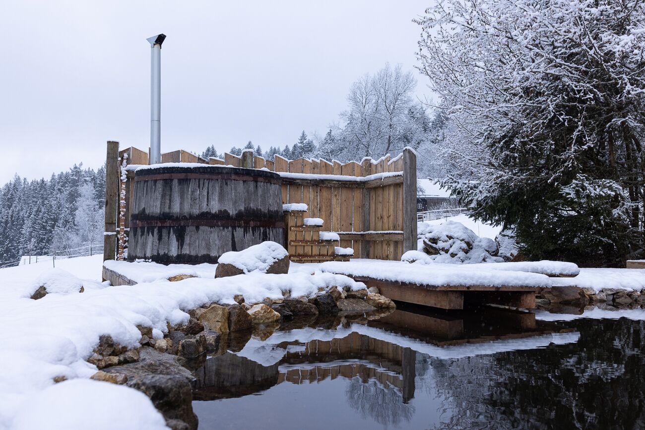 A wooden structure with a stone base, surrounded by snow-covered ground and trees.