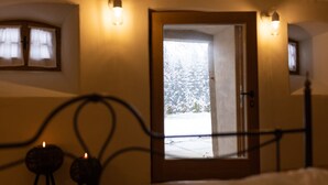 Una habitación con una cama, una puerta que da al exterior y dos lámparas fijadas a la pared.
