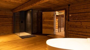 Un baño moderno con paredes de madera, cabina de ducha de vidrio y una bañera grande.
