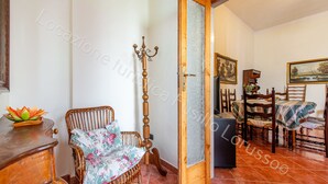Ein Zimmer mit einem Korbstuhl, einer Holztür, einem Esstisch mit Stühlen und einem Bild an der Wand.