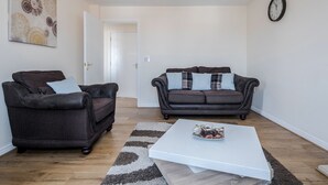 A living room with two dark leather sofas, a white coffee table, and a patterned rug. - Captivating 3-bed Apartment in Grays (Grays)