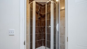 A shower with a glass door, white walls, and brown tiles. - Captivating 3-bed Apartment in Grays (Grays)