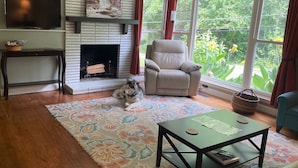 Una sala de estar con chimenea, un sofá, una mesa de centro y un perro.