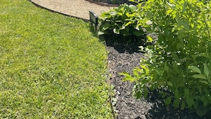 Una propiedad residencial con un césped cuidado, una cerca de madera y un patio cubierto.