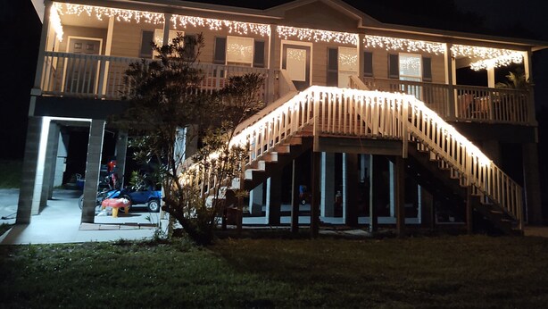 A two-story house with a covered porch and a staircase leading to the upper level.