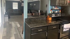 A modern kitchen with black cabinets, a granite countertop, and a stainless steel microwave.