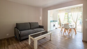 Ett vardagsrum med en grå soffa, ett vitt soffbord och en matplats med vita stolar och ett bord.