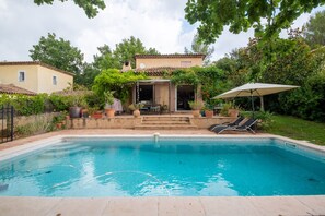 A rectangular swimming pool with clear blue water, surrounded by a patio area with lounge chairs and an umbrella. - Studio with a swimming pool in a quiet location near golf courses and a nature park, Sophia Technology Park (Valbonne)