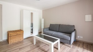 Ett modernt vardagsrum med en grå soffa, ett vitt soffbord och en korg av rotting.