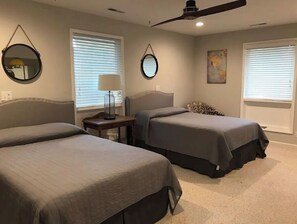Two single beds with matching headboards, a nightstand, and a ceiling fan.