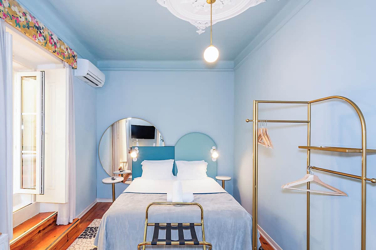 A bedroom with a bed, bedside tables, a mirror, and a hanging clothes rack.
