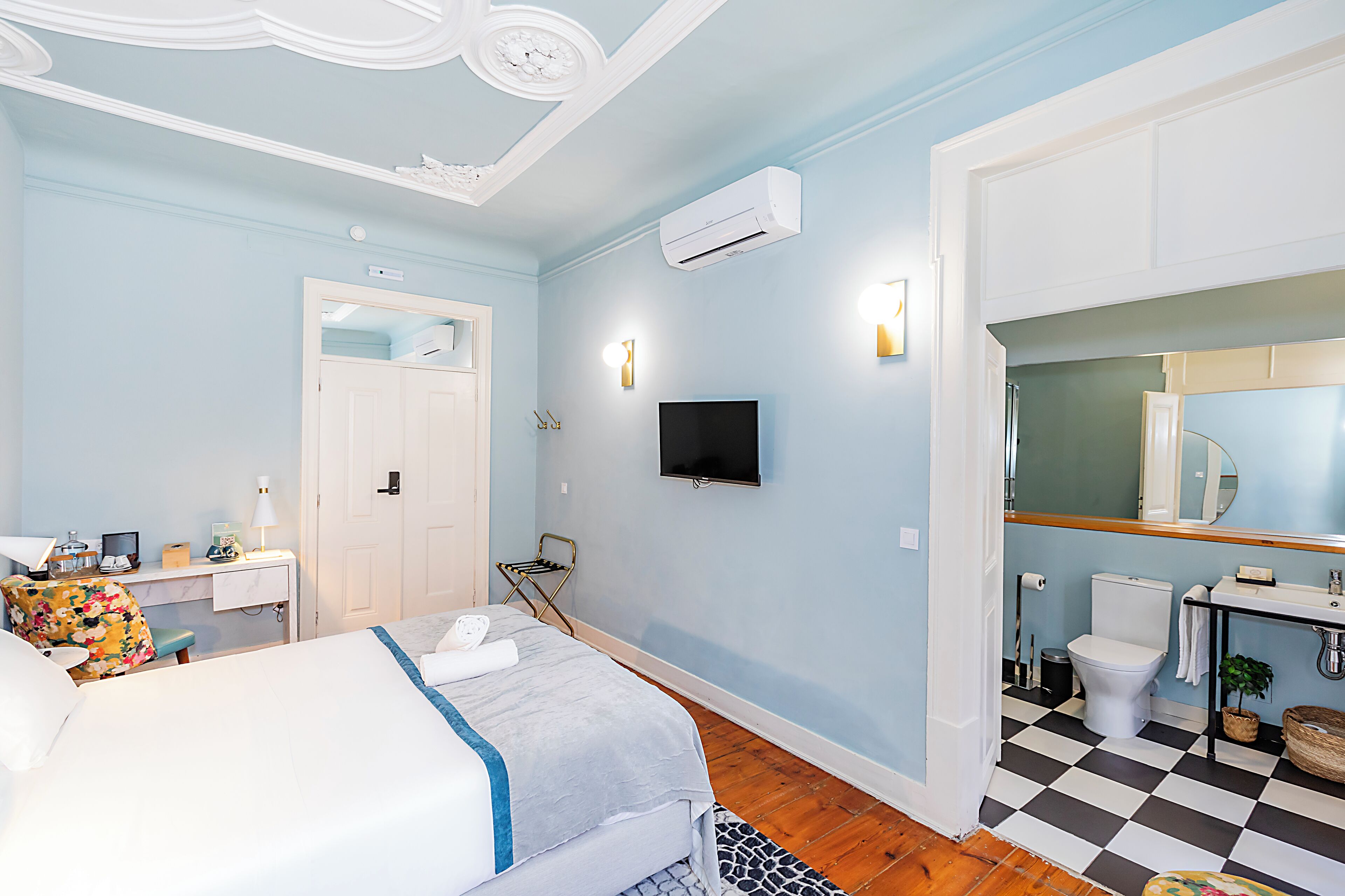 Een hotelkamer met een bed, bureau, stoel, televisie en badkamer.