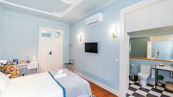 Een hotelkamer met een bed, bureau, stoel, televisie en badkamer.
