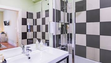 A bathroom with a white sink, a glass shower enclosure, and black and white checkered tiles.