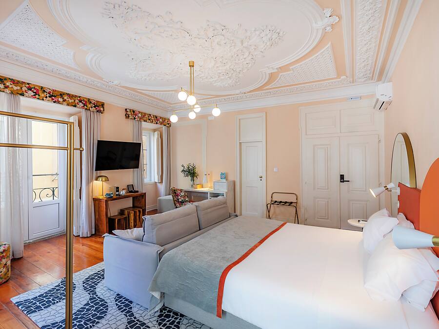 Una habitación de hotel con una cama grande, un sofá, un escritorio con una computadora y un televisor.