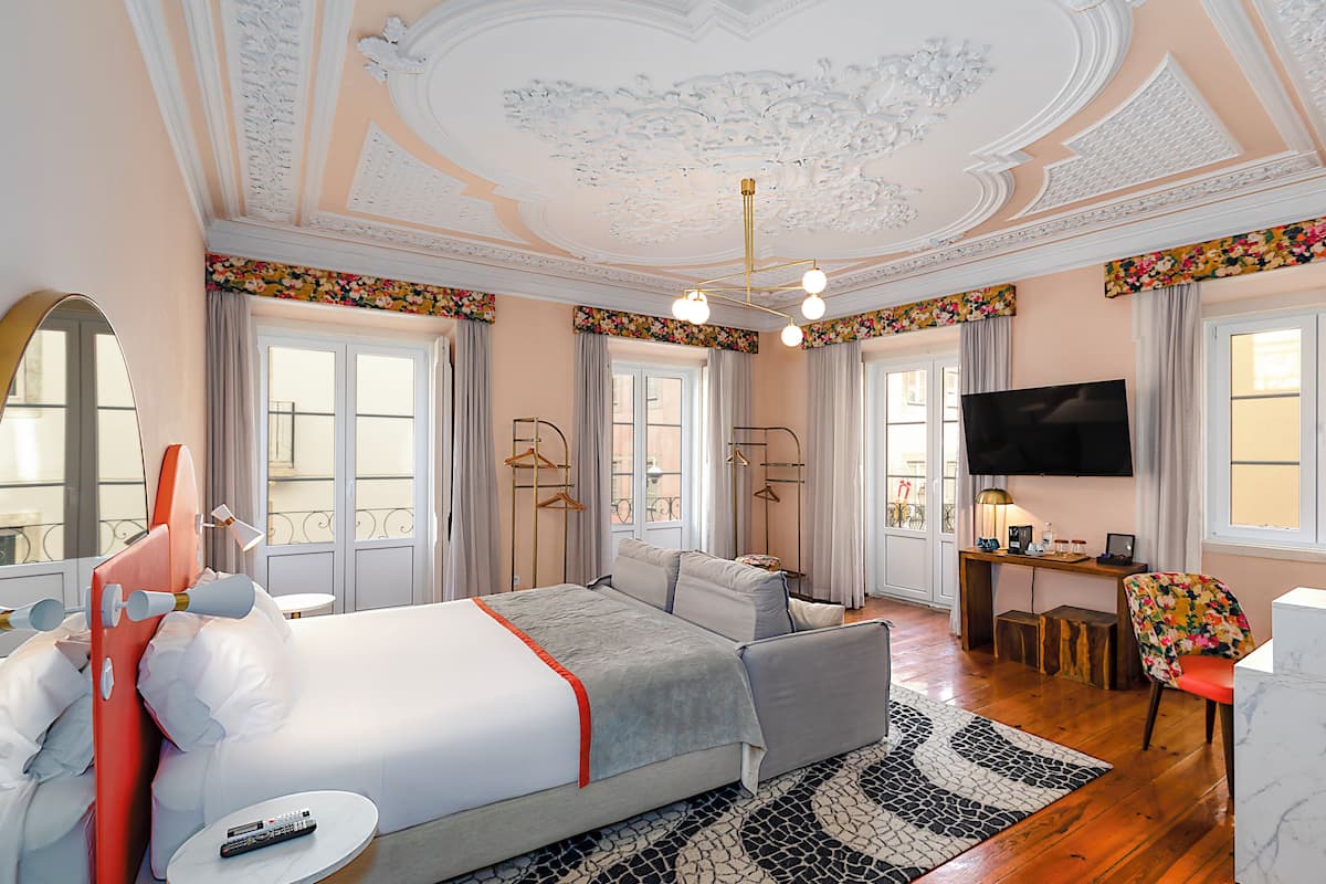 A hotel room with a large bed, a TV, a desk, and a chair.