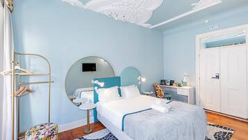 A bedroom with a bed, a round mirror, a bedside table, a wardrobe, and a bathroom with a sink and mirror.