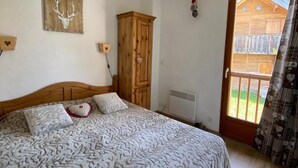 A bedroom with a bed, wooden wardrobe, and a ceiling fan. - Chalet, 350m from ski slopes, view mountain, swimming pool, sauna, terrace, parking, tv, ski locker (Agnières-en-Dévoluy)