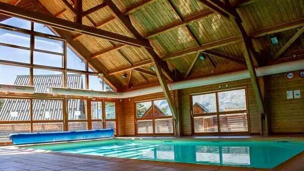 An indoor swimming pool with a high wooden ceiling and large windows. - Chalet, 350m from ski slopes, view mountain, swimming pool, sauna, terrace, parking, tv, ski locker (Agnières-en-Dévoluy)