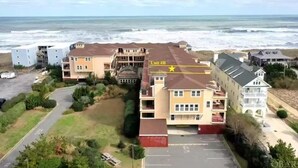 Un quartier résidentiel situé sur la côte, avec des immeubles à plusieurs étages, un parking et une vue sur l’océan.