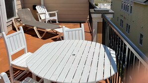 Une terrasse avec une table ronde et des chaises blanches, donnant sur une plage.