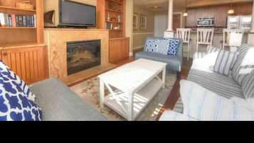 A living room with a fireplace, a television, and a dining area with chairs and a table.