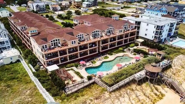 Un hôtel à plusieurs étages doté d’une piscine et d’un accès à la plage.
