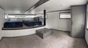 A compact room with two beds, a small table, and a wardrobe.